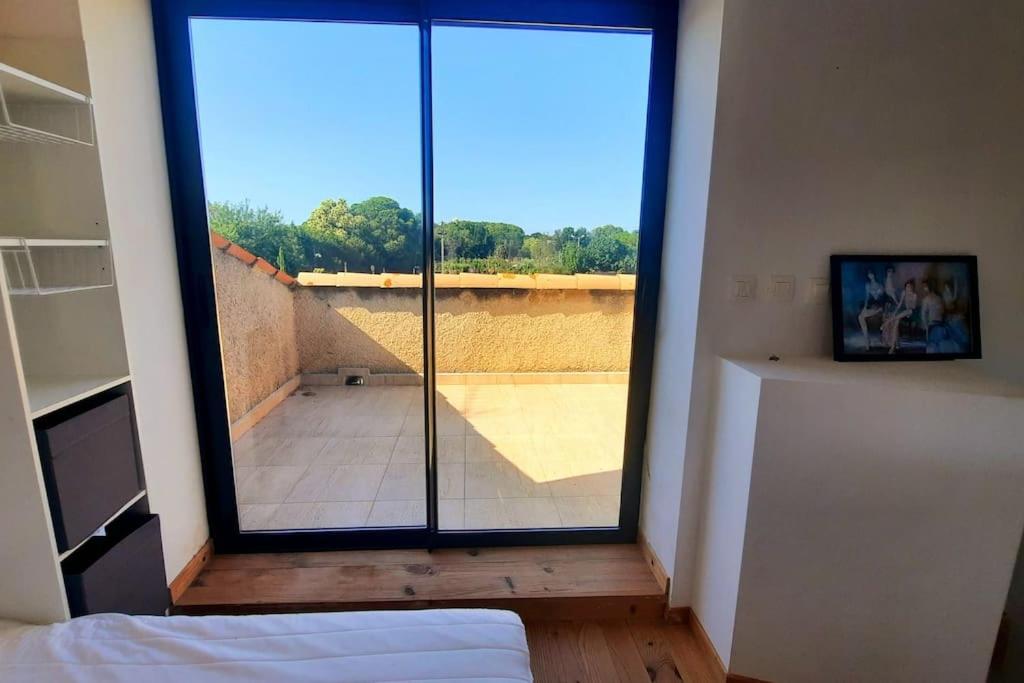 una camera da letto con una grande porta a vetri che conduce a un balcone di La Cigale - Piscine - Centre village a Bessan