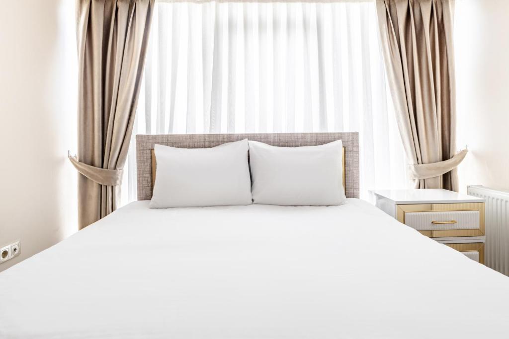 uma cama com almofadas brancas em frente a uma janela em Flat with Terrace 1 min to Trump Towers em Istambul