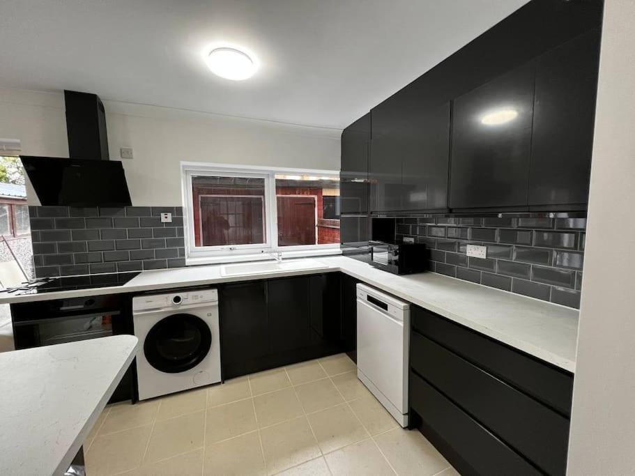 a kitchen with black cabinets and a washer and dryer at Springfield House- Near Newcastle Centre, Hospital and Keele University! in Stoke on Trent