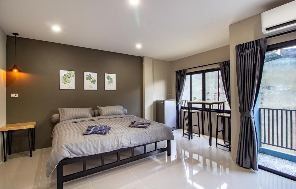 a bedroom with a large bed and a table at Is Am Are Stay Boutique in Ratchaburi