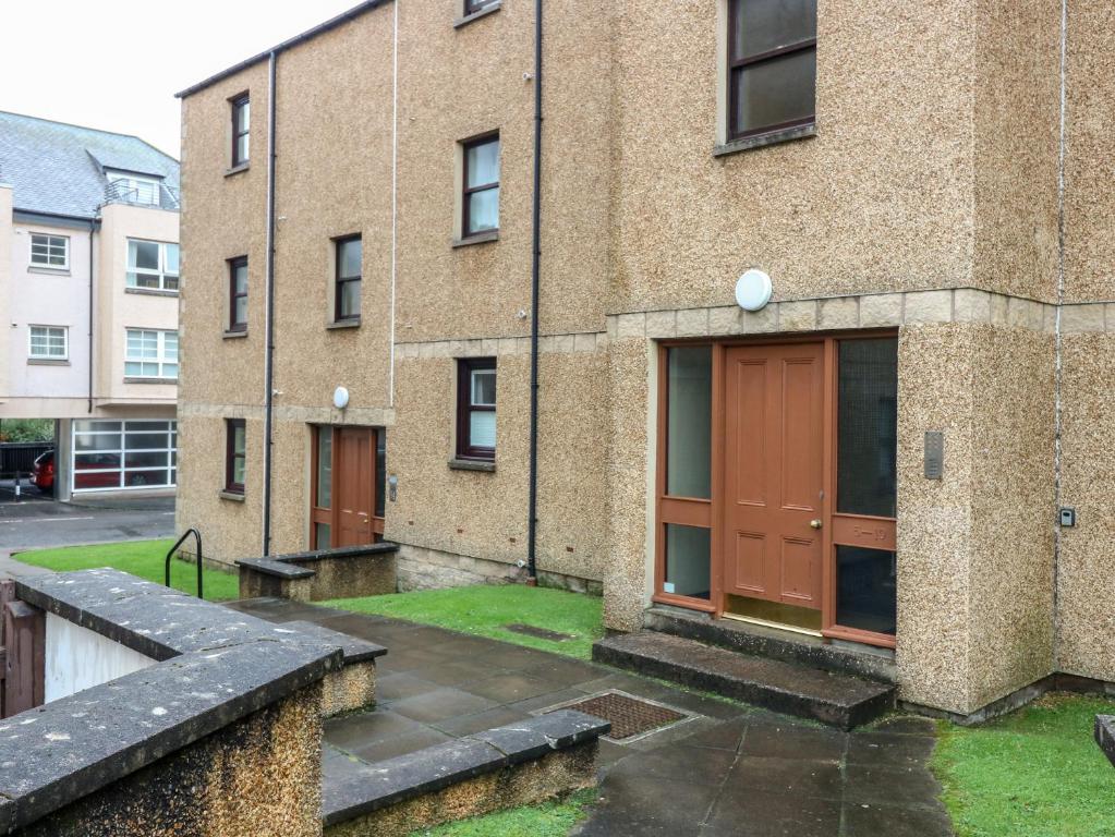 a brick building with red doors and grass outside at The Kate Kennedy Apartment in St Andrews