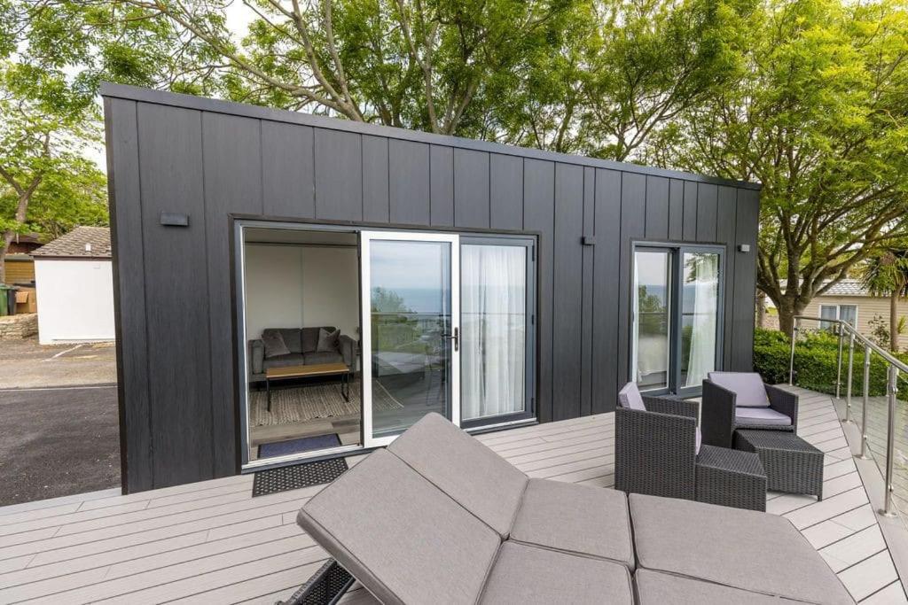 a black tiny house with a patio and chairs at Upper Cliff Studio in Portland