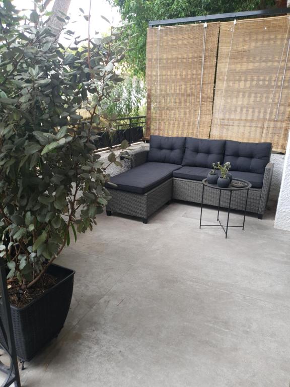 eine Terrasse mit einem blauen Sofa und einem Tisch in der Unterkunft Poros Maisonette Apartment - Neorio in Poros