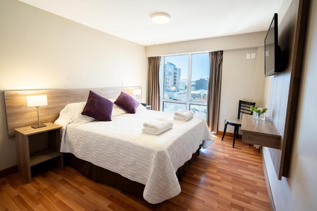 Una habitación de hotel con una cama y una ventana grande. en Lagos Andinos, en San Carlos de Bariloche