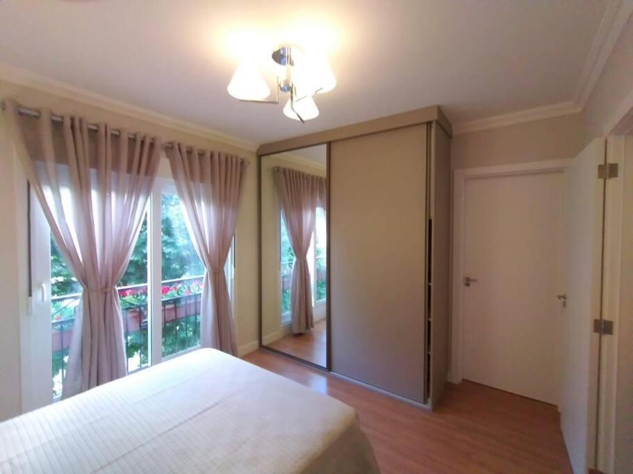 ein Schlafzimmer mit einem Bett und einem großen Spiegel in der Unterkunft Apartamento novo centro de Canela in Canela