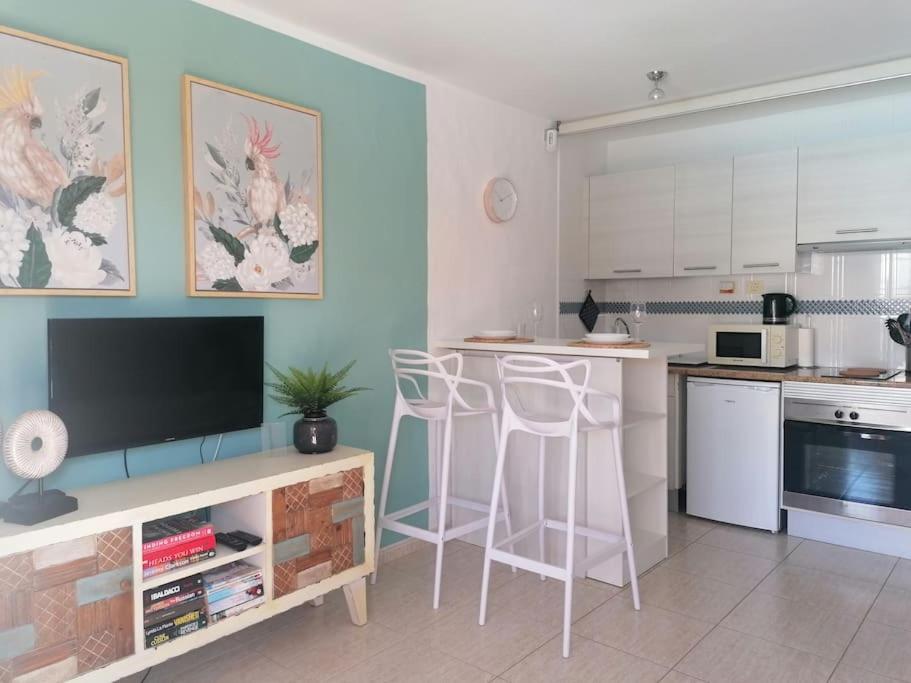 una cucina con TV e bancone con sgabelli di Casa Naturaleza 2 a Caleta De Fuste
