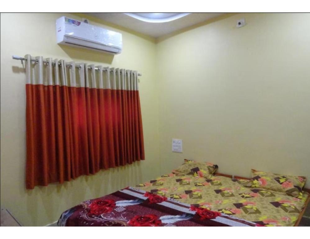 Hotel Shree, Somnath في سومناث: غرفة نوم بسرير وستارة حمراء