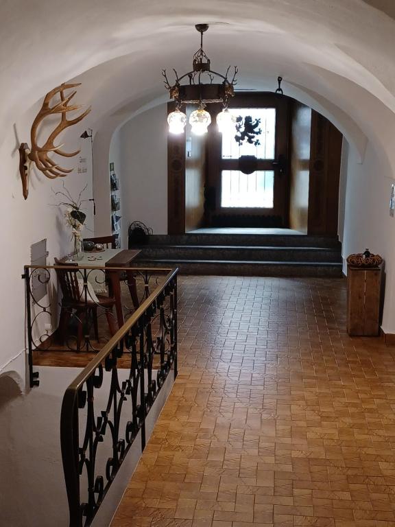 a hallway with a staircase with a window and a chandelier at Hotel Garni Löwen in Silz