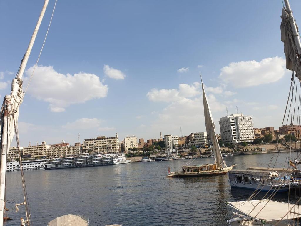 una barca a vela e una barca in un fiume con una città di Onaty Narty Guest house a Aswan