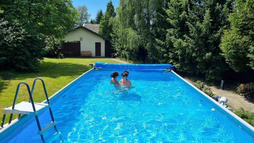 two girls are standing in a blue swimming pool at Emerald Spa Guest house in Kraków