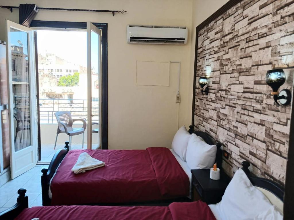 a bedroom with a red bed and a brick wall at New Palace Hotel in Cairo