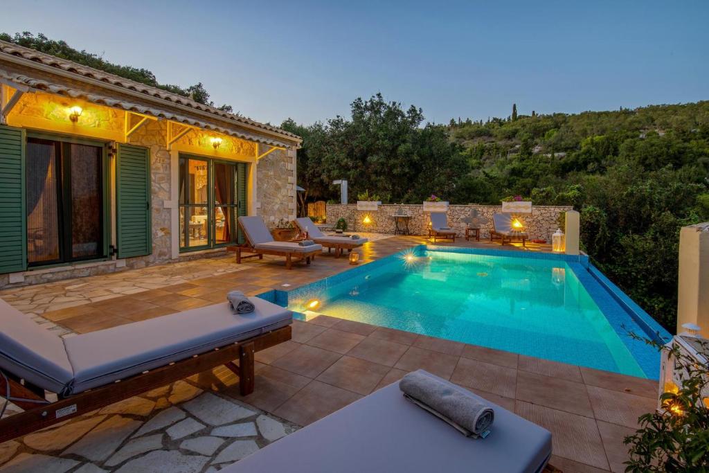 a swimming pool with a patio and a house at Lilac Lilium Artistsvillas in Gaios