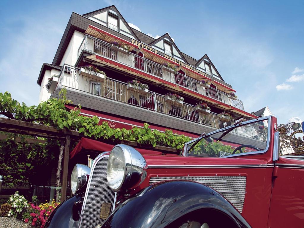 une vieille voiture rouge garée devant un bâtiment dans l'établissement Hotel Garni Rheinpracht, à Kamp-Bornhofen