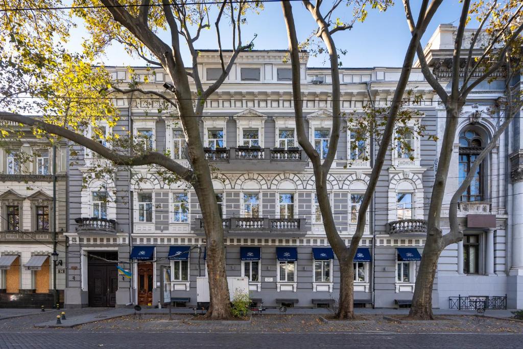 un bâtiment blanc avec des arbres devant lui dans l'établissement Metro Hotel Apartments, à Odessa