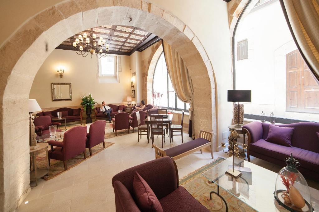 a waiting room with purple chairs and tables and windows at Algilà Ortigia Charme Hotel in Siracusa