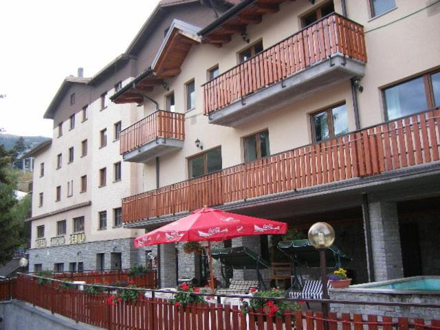 a restaurant with an umbrella in front of a building at Hotel Savoia Debili in Sauze dʼOulx