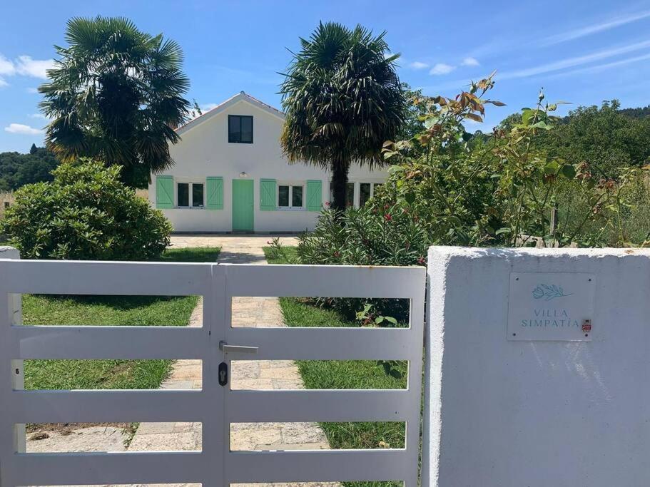una cerca blanca frente a una casa con palmeras en Villa Simpatía en Merza