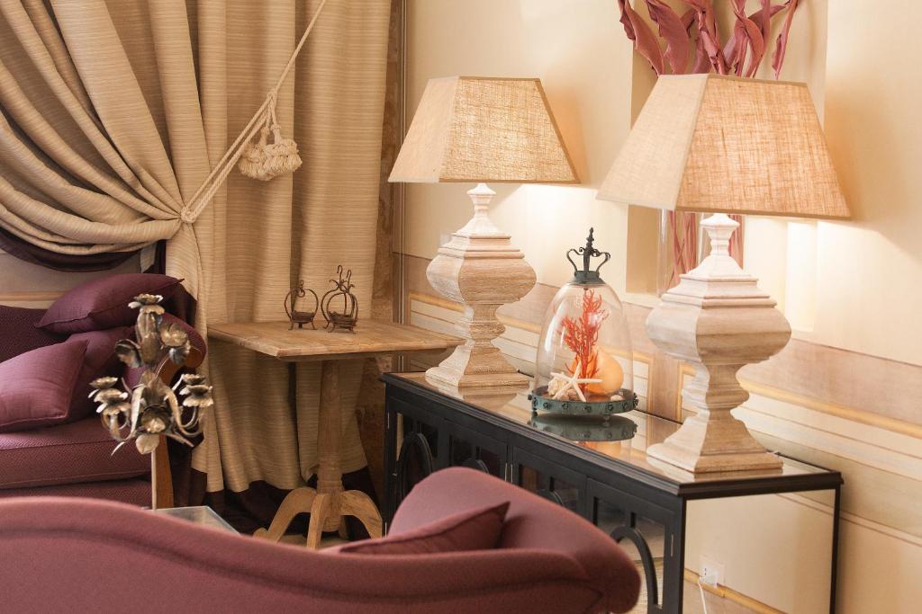 a living room with two lamps on a table and a chair at Algilà Ortigia Charme Hotel in Siracusa