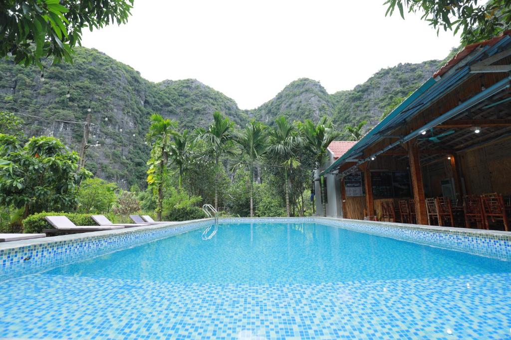 una piscina con sillas y montañas en el fondo en Tam Coc Luxury Homestay, en Ninh Binh