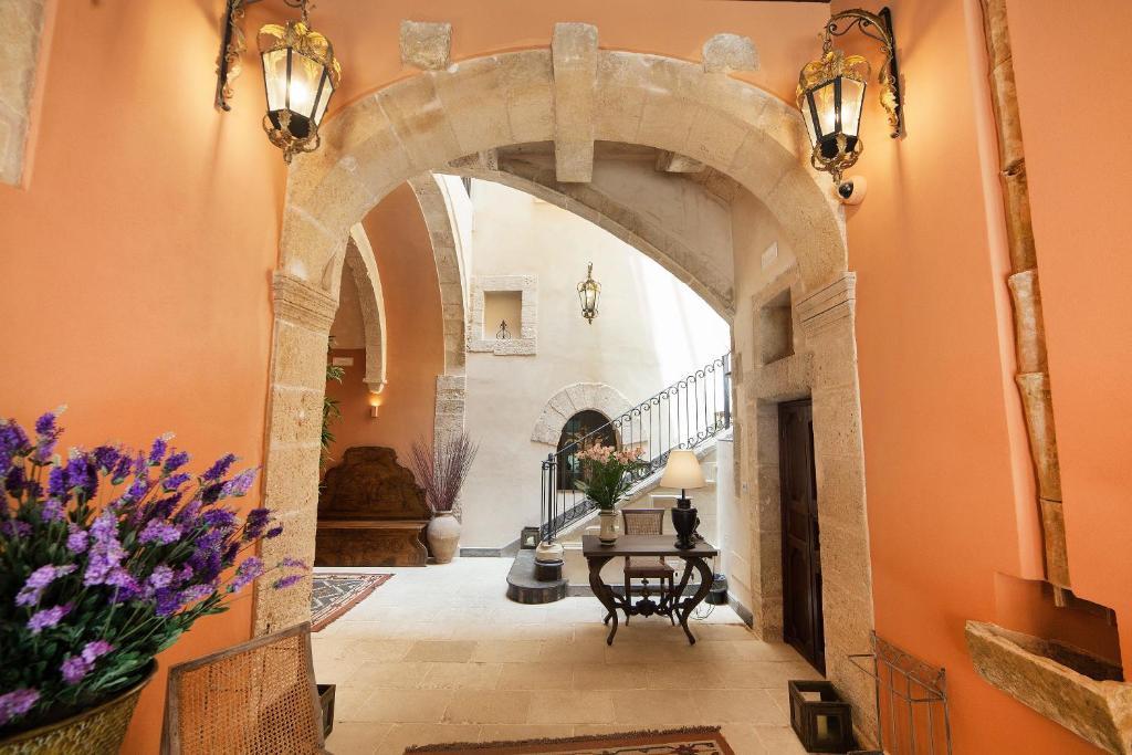an archway in a hallway with a table and flowers at Algilà Ortigia Charme Hotel in Siracusa