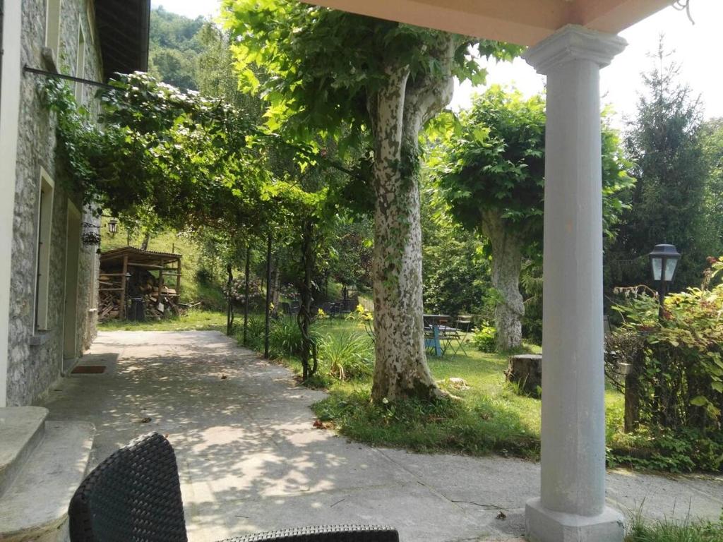 een veranda van een huis met een stoel en bomen bij Casale La Selva Cottege grande in Piano Porlezza