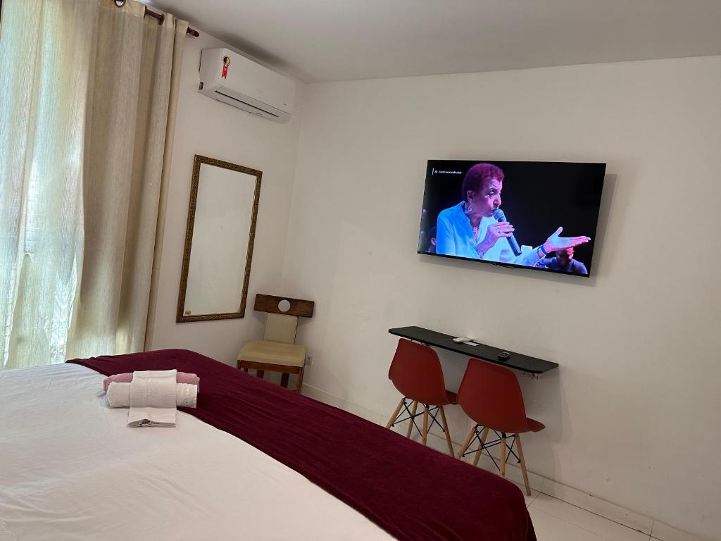 um quarto com uma cama e uma televisão na parede em Suite Real Residencial no Rio de Janeiro