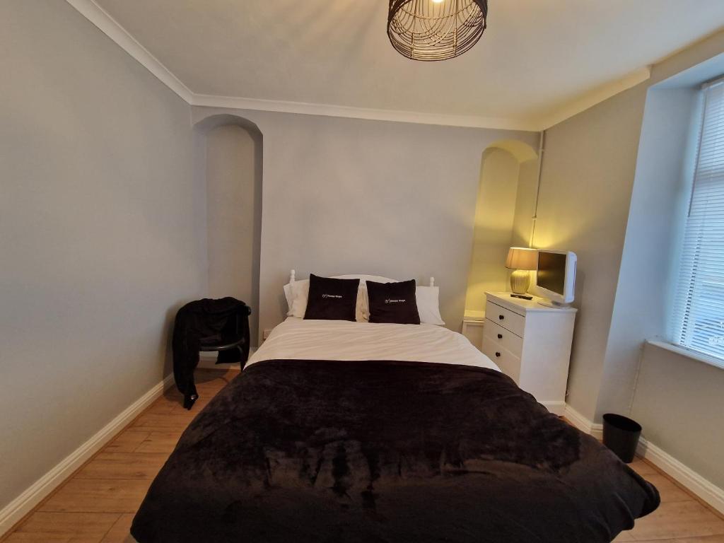 a bedroom with a large bed with a black blanket at 4 Bedroom house in Merthyr Tydfil. Near Brecon Beacons National Park in Dowlais