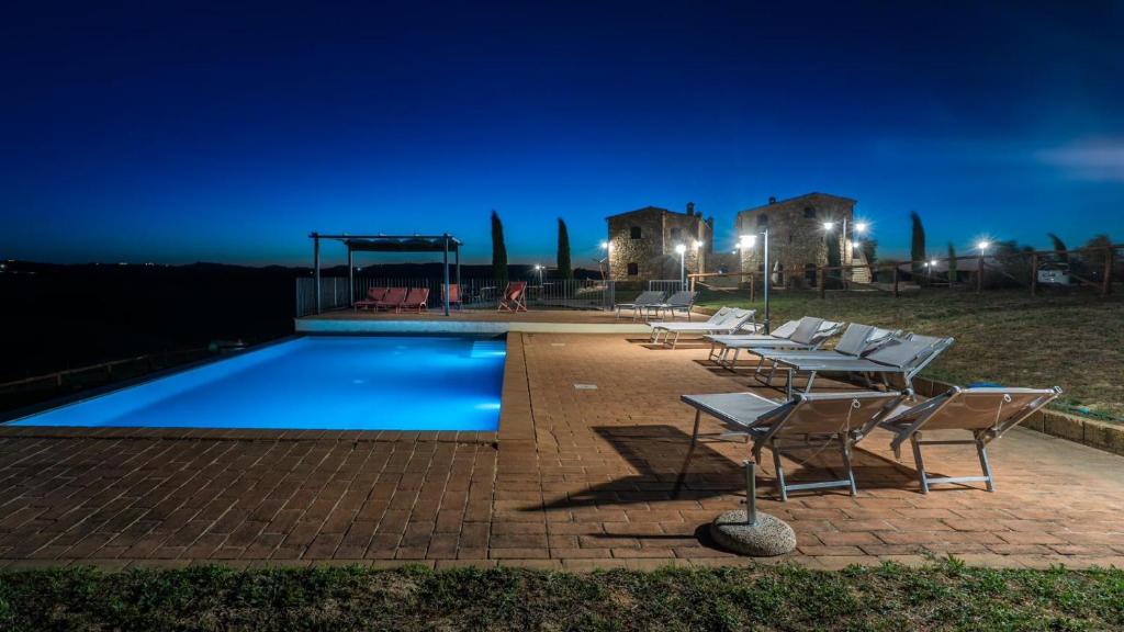 una piscina con sillas y un cenador por la noche en Casa Girasole Podere Fossaccio, en Asciano