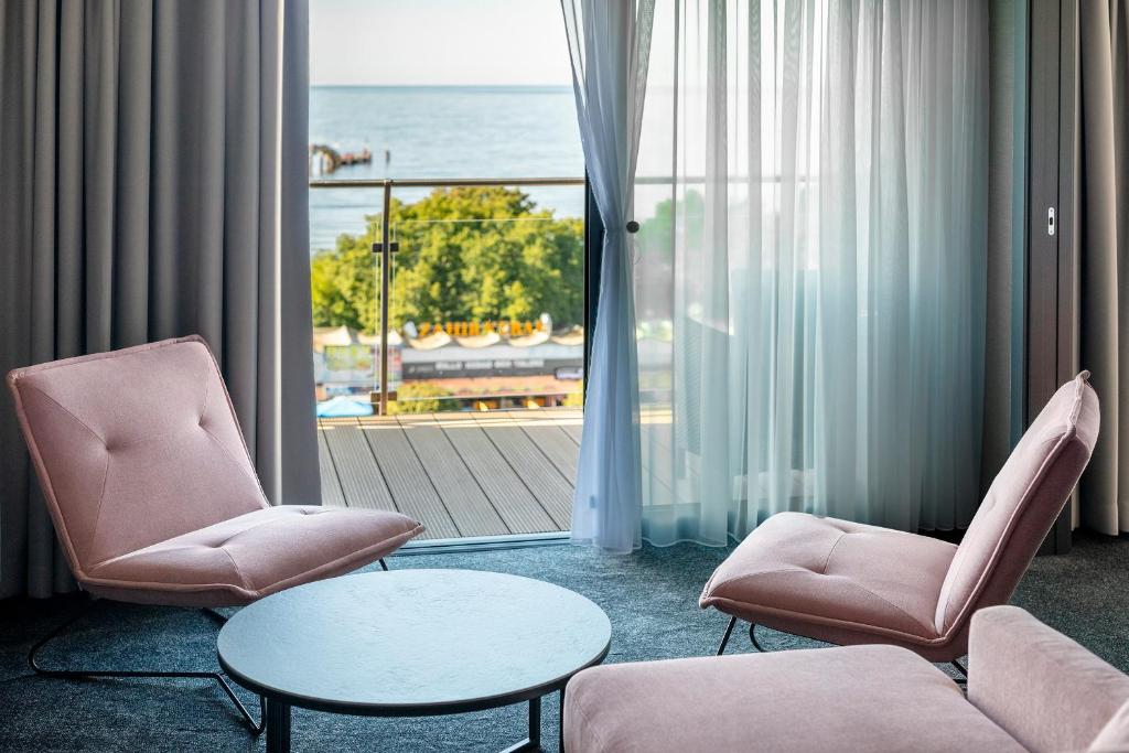 a room with two chairs and a table and a window at Hotel Aurora Family & SPA in Międzyzdroje