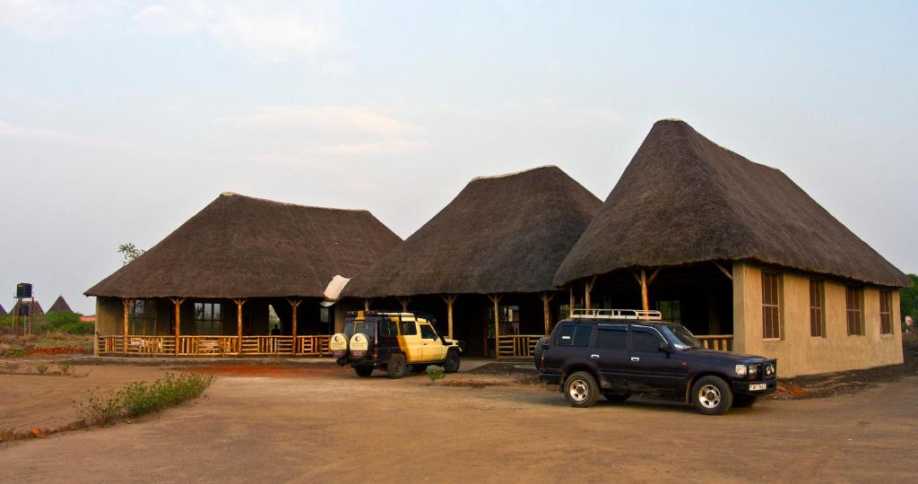 due camion parcheggiati di fronte a un edificio con tetti di paglia di Euphorbia Safari Lodge a Kasenyi