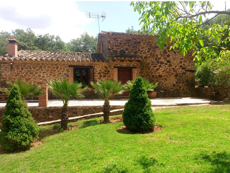 una casa de piedra con árboles en un patio en FINCA LA LISERILLA, en Galaroza