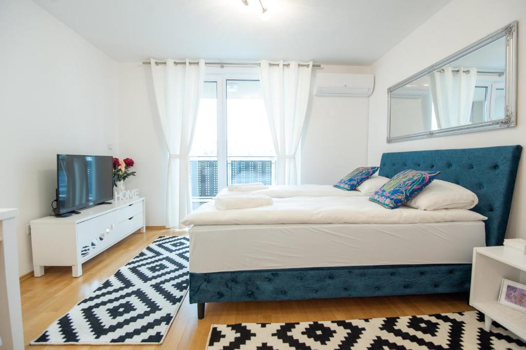 Schlafzimmer mit einem Bett mit blauem Kopfteil und einem TV in der Unterkunft Lovely Studio Close to Center in Sarajevo