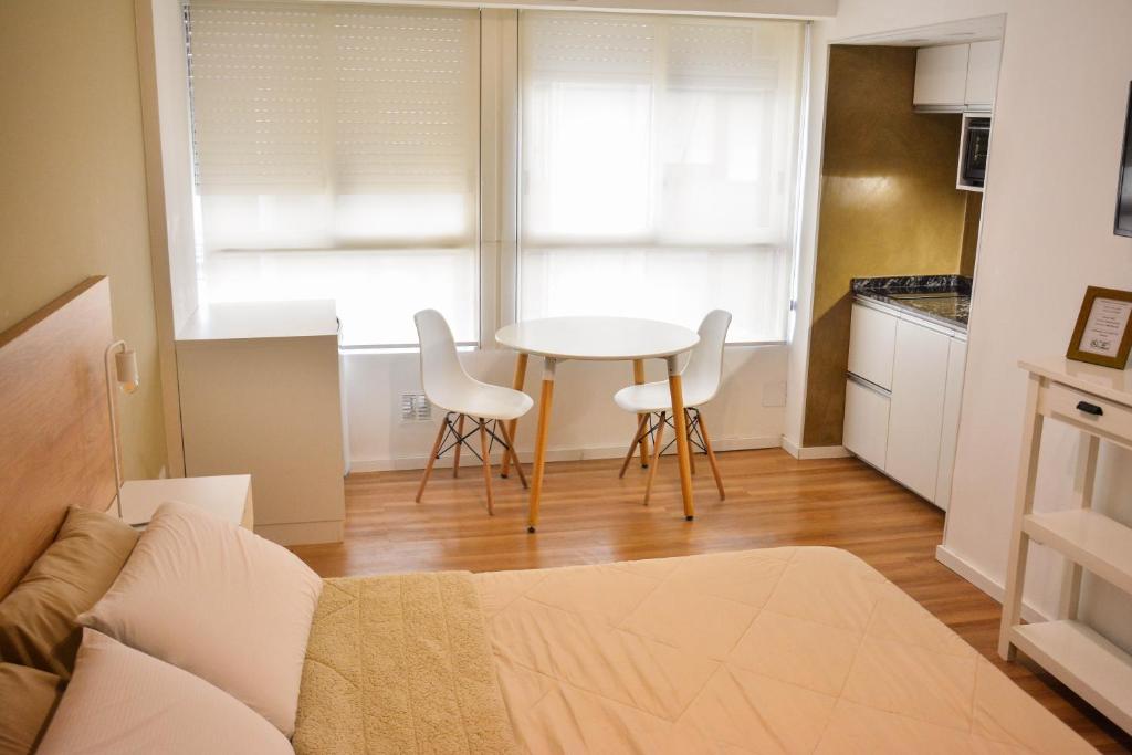 ein Wohnzimmer mit einem Tisch und 2 weißen Stühlen in der Unterkunft Studio Congreso in Buenos Aires