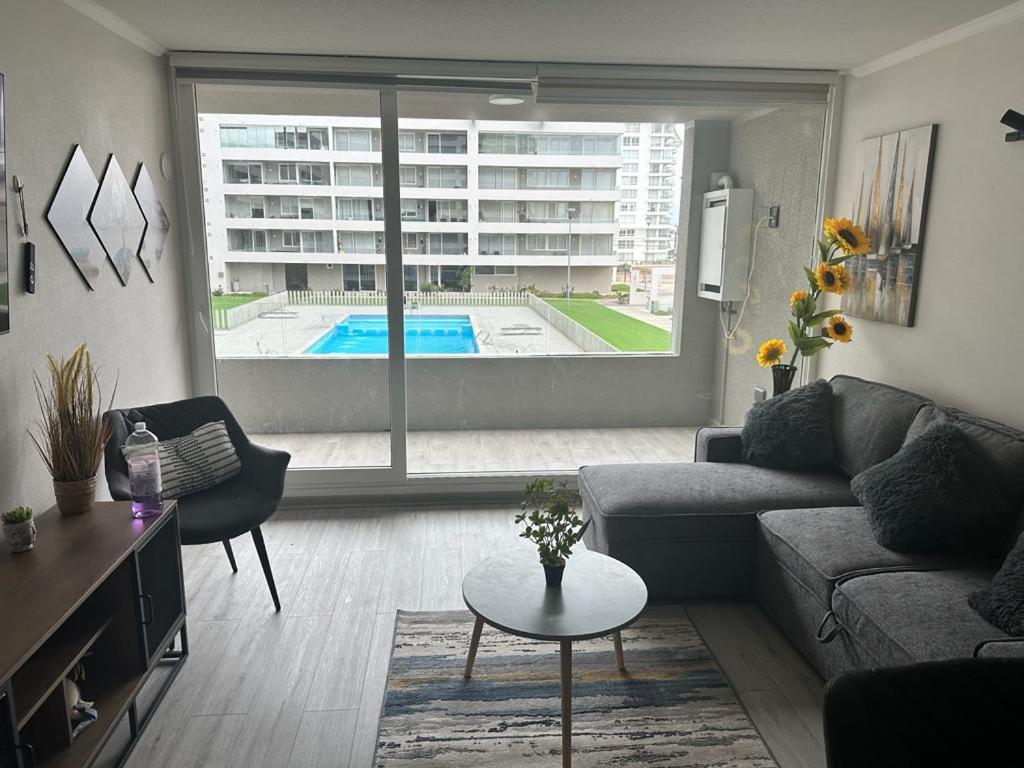 ein Wohnzimmer mit einem Sofa, einem Tisch und einem Pool in der Unterkunft Departamento La Serena in La Serena