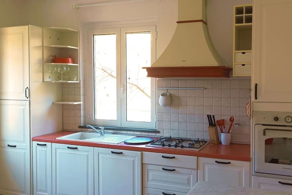 eine Küche mit weißen Schränken, einem Waschbecken und einem Fenster in der Unterkunft Casa Mariel in La Spezia