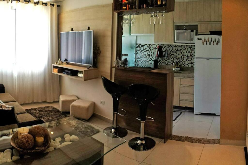 Votorantim的住宿－Apto mobiliado -48m² próximo ao shopping Iguatemi，厨房以及带桌子和冰箱的客厅。