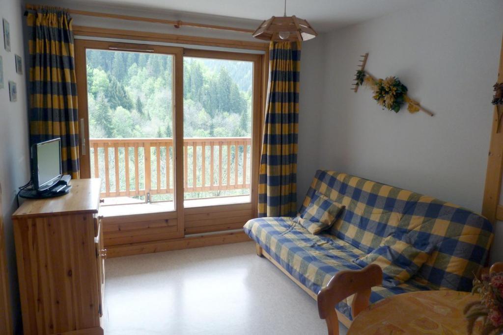 un salon avec un canapé et une grande fenêtre dans l'établissement Appartement cosy, 4 personnes, 1 chambre, 1 coin montagne - CC07, à Beaufort