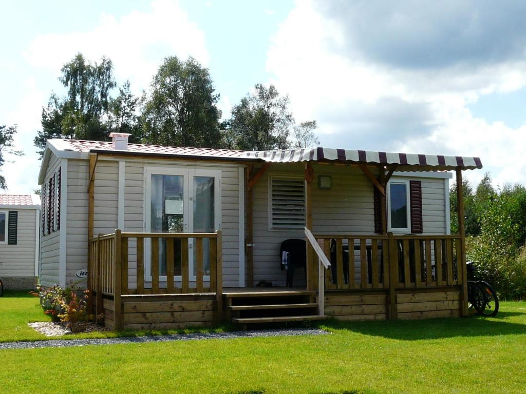 une petite maison avec une terrasse couverte et une terrasse dans l'établissement Ferienpark Auf dem Simpel - Mobilheim 4, à Soltau