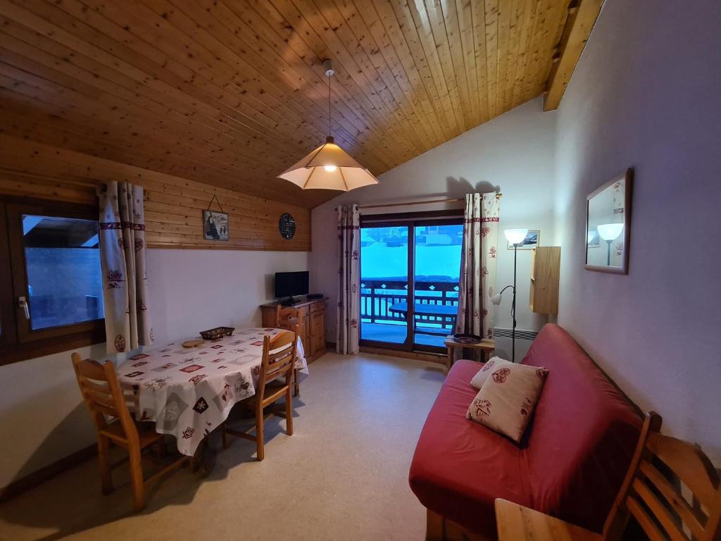 - une salle à manger avec une table et un canapé rouge dans l'établissement Appartement pied des pistes, 6 personnes, 2 chambres - GRAN11, à Beaufort