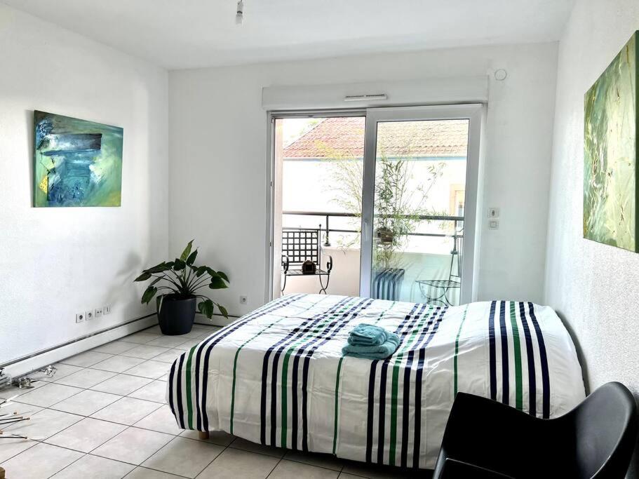 een slaapkamer met een bed en een groot raam bij Bright and quiet apartment - free parking in Illzach