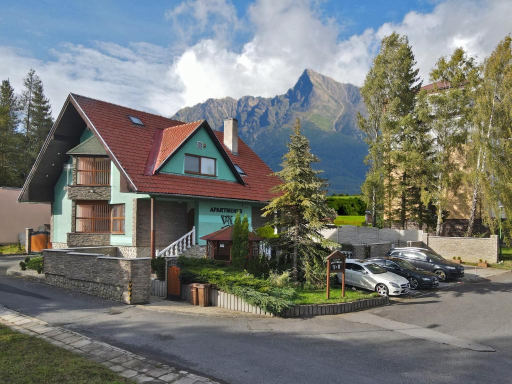 une maison avec des voitures garées devant elle et une montagne dans l'établissement APARTMENTS V+K, à Tatranska Strba