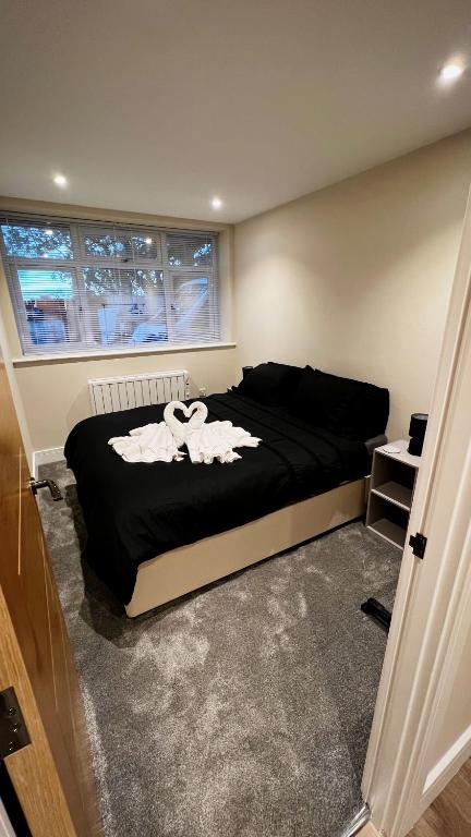 a bedroom with a black bed with towels on it at Abbey House in Horsham