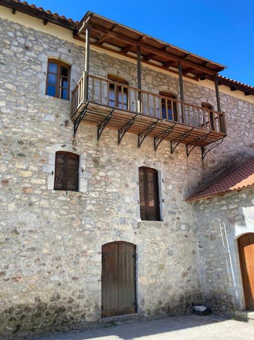- un vieux bâtiment en pierre avec une porte en bois et un balcon dans l'établissement Παραδοσιακή Κατοικία στο Μαίναλο, à Alonistaina