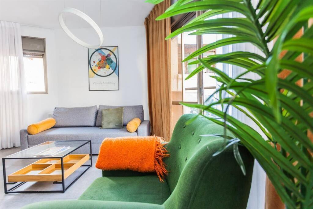 ein Wohnzimmer mit einem grünen Sofa und einem Glastisch in der Unterkunft 3Bedroom Suite with balcony Yona Hotel in Tel Aviv