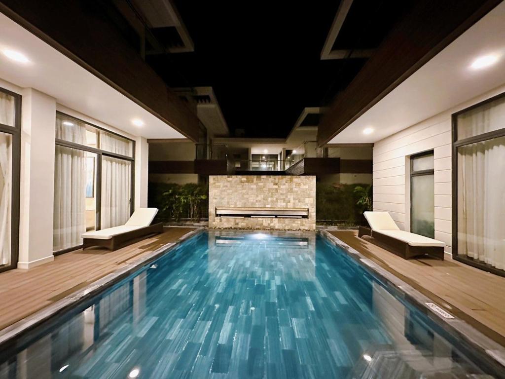 a swimming pool with two chairs and a fireplace in a building at Phoenix Pool Villa Cam Ranh in Cam Ranh
