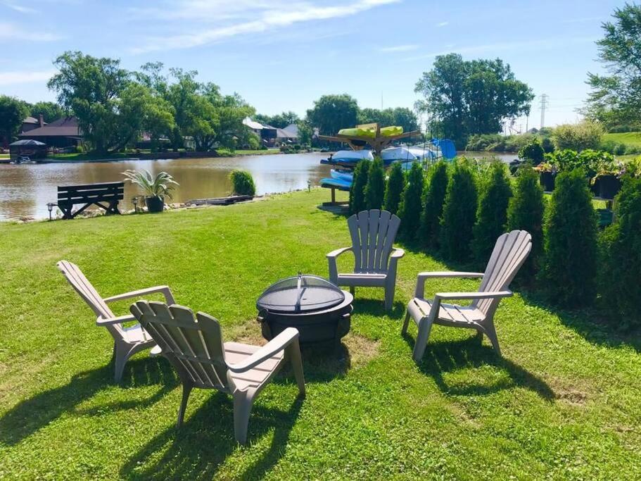 a group of chairs and a fire pit in the grass at 2 bedroom Getaway on the River/close to marina in Belle River
