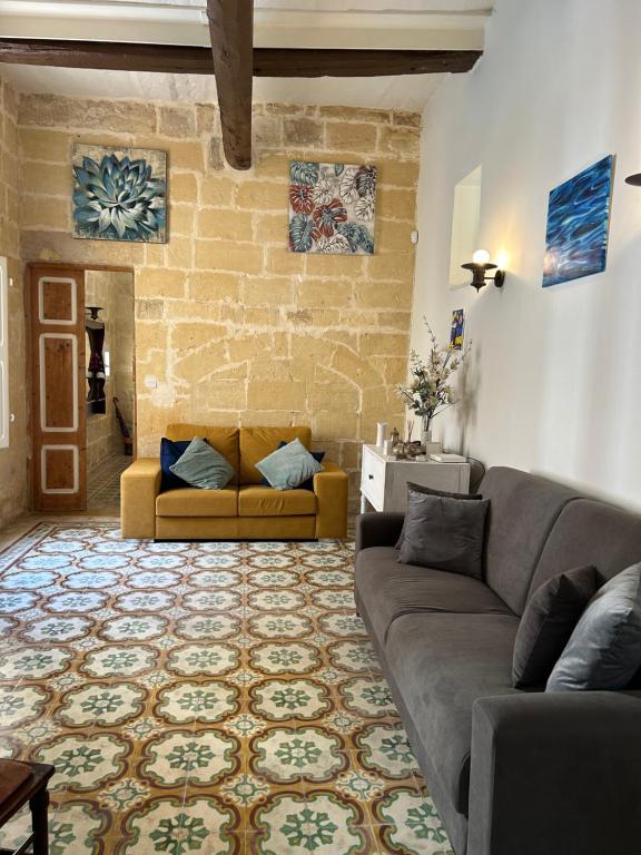 a living room with a couch and a brick wall at The Gem Farmhouse in Qormi