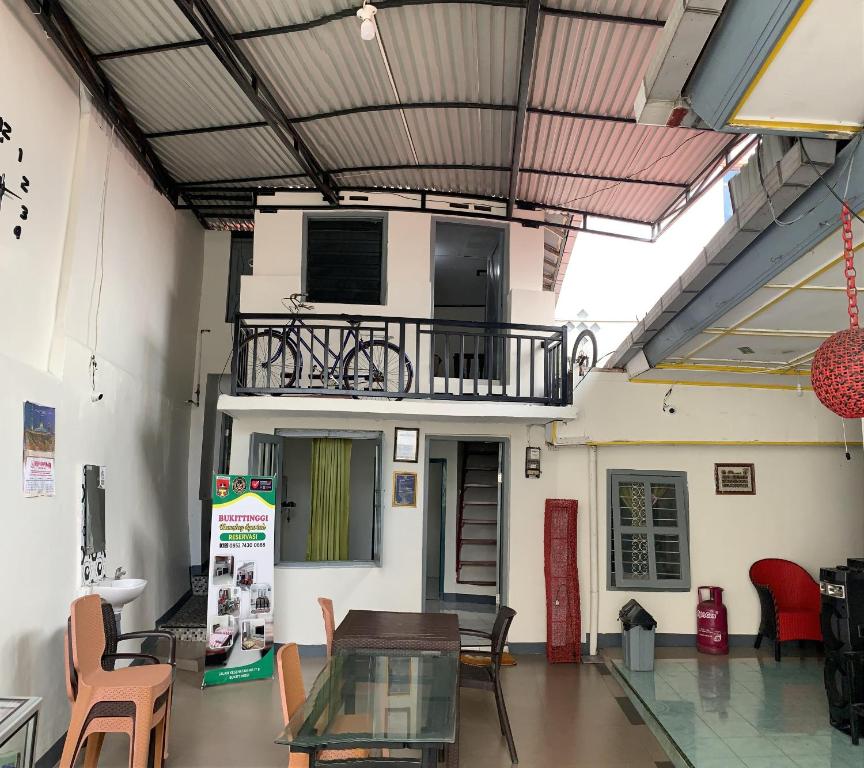 ein Gebäude mit einem Balkon mit einem Tisch und Stühlen in der Unterkunft Bukittinggi Homestay in Bukittinggi
