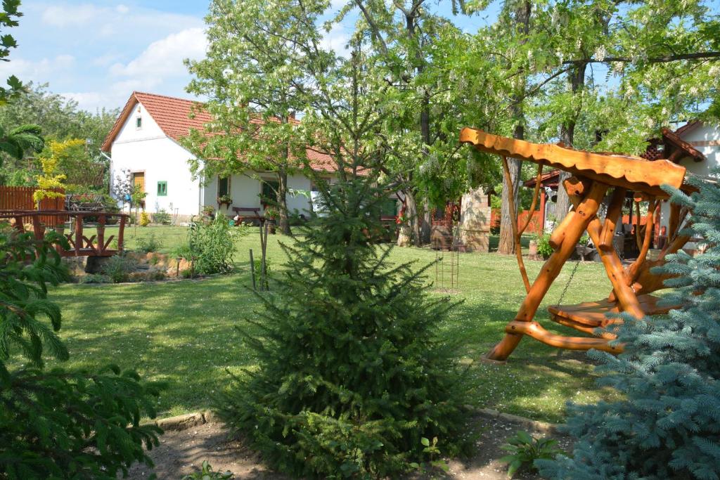 a wooden playground in a yard with a house at Németh Tanya Vendégház in Pusztaszer