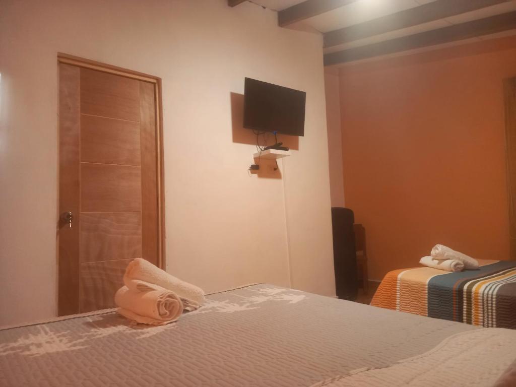 a bedroom with two beds and a television on the wall at Hospedaje Campestre Los Suspiros in Sunampe